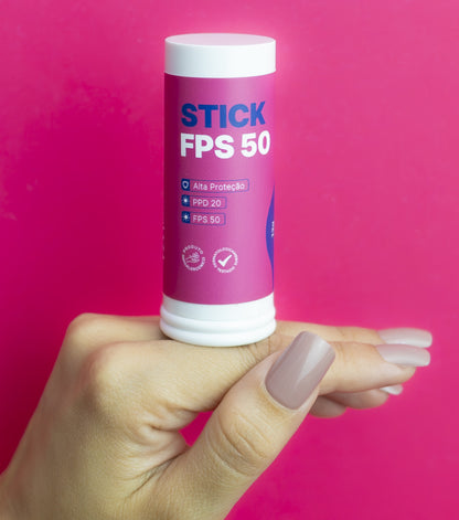 Mão segurando o Stick FPS 50 Peak Beauty sobre fundo rosa