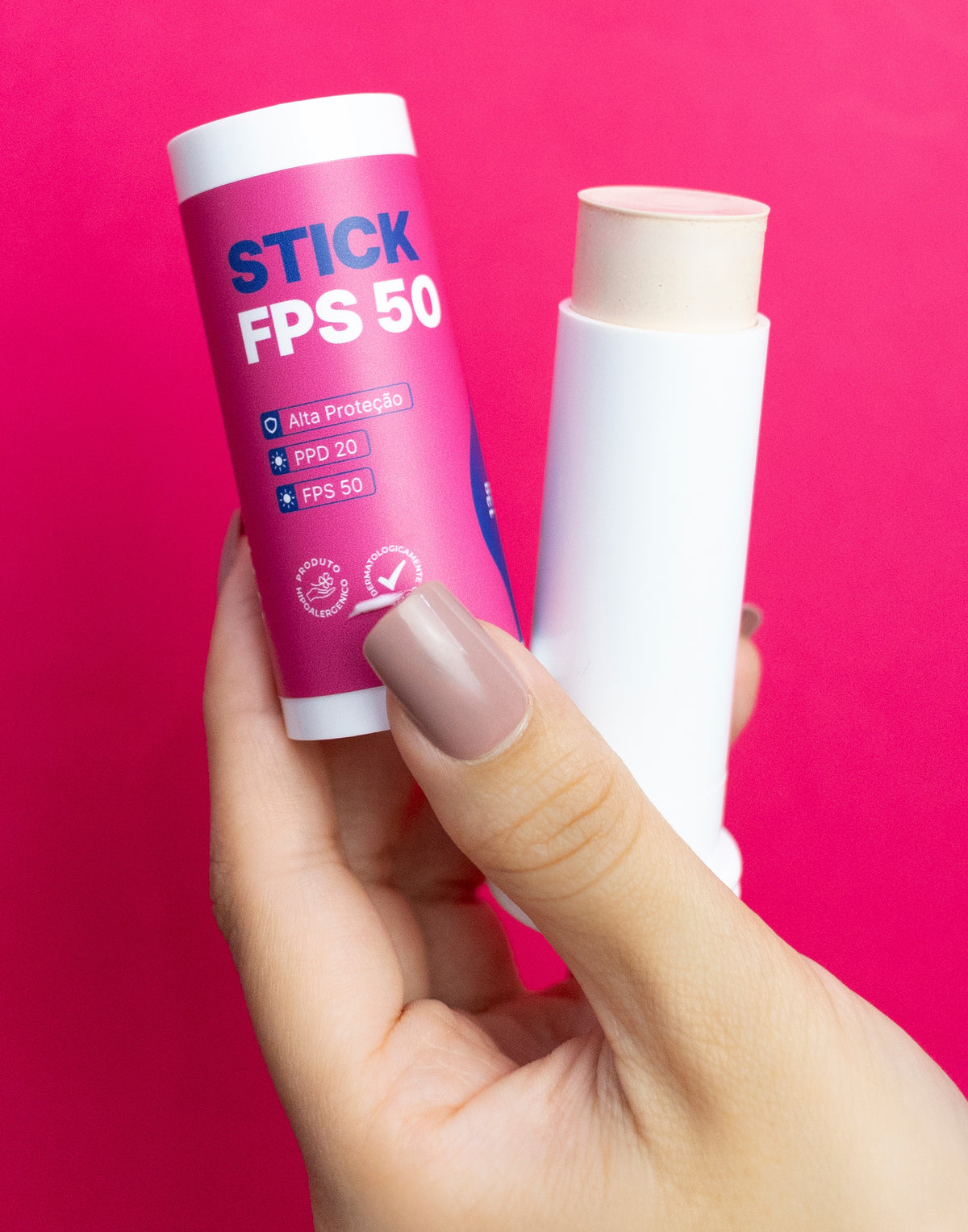 Mão segurando o Stick FPS 50 aberto, pronto para aplicar no rosto