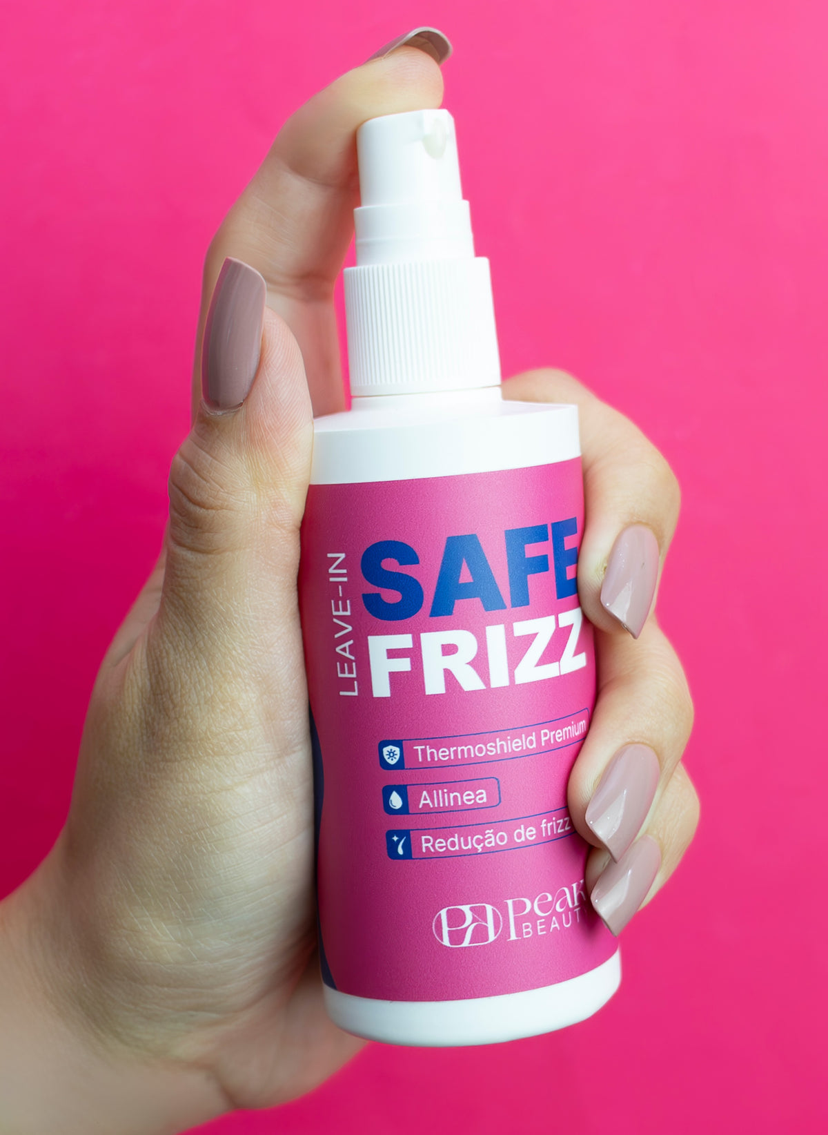 Mão segurando o leave-in Safe Frizz Peak Beauty sobre fundo rosa